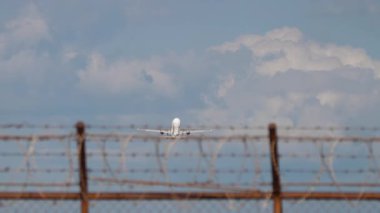 Arkadan çekilen, bulutlarla dolu mavi bir gökyüzüne tırmanan bir uçağın videosu. Giderken uçağın uzaktan görüntüsü.