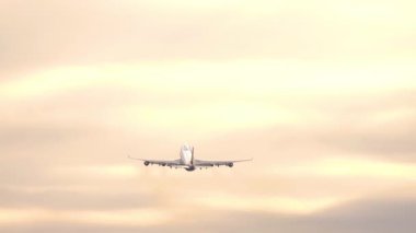 Geniş gövdeli dört motorlu jet güneş doğarken ya da batarken gökyüzüne tırmanıyor. Seyahat ve uzun mesafe havacılık konsepti.