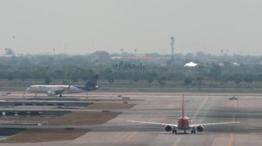 BANGKOK, THAILAND - 15 Mart 2025: ThaiVietjet Air Airbus A321, HS-VKH Bangkok havaalanında taksicilik, arka görüş. Uçak kalkıyor. Tayland Havayolları arka planda taksicilik yapıyor. Beneklenme