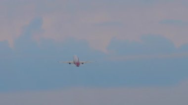 Kalkıştan sonra gökyüzüne tırmanan bir yolcu uçağının uzaktan görünüşü, hava yolculuğunu ve havacılığı temsil ediyor.