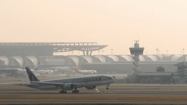 BANGKOK, THAILAND - 17 Mart 2025: Geniş gövdeli Boeing 777, Katar 'ın A7-BEV uçakları Suvarnabhumi havaalanından havalanıyor, yan görüş. Seyahat kavramı