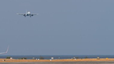 PHUKET, THAILAND - 17 Şubat 2025: Uzak çekim, Indigo Airbus A320 uçağı, VT-IXH iniş. Deniz kıyısındaki havaalanı.