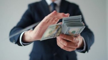 Formally dressed man makes money rain from US dollar bills. Slow motion. Concept of investment, success, financial prospects or career advancement