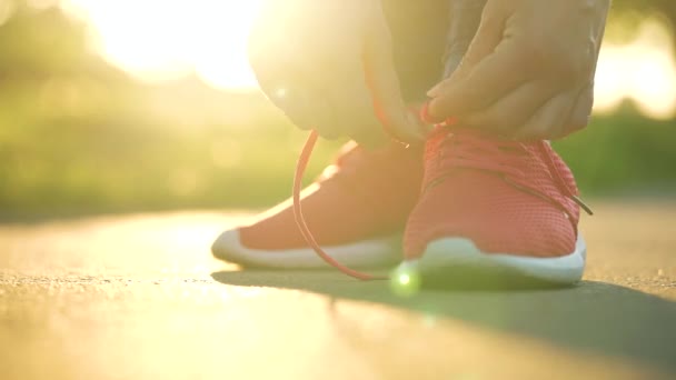 ジョギングや日没時に歩いている間に靴ひもを結ぶ女性 閉じる — ストック動画