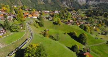 İsviçre 'nin güzel doğası ve Lauterbrunnen köyünün havadan görünüşü, tren, dağ yolunda yavaş ilerliyor. Ünlü İsviçre turizm beldesi.