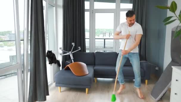 Hombre Limpiando Casa Divirtiéndose Bailando Cantando Con Una Escoba Gato — Vídeos de Stock