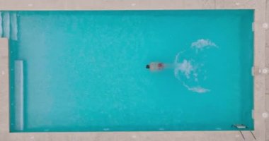 Top down view as a man dives into the pool and swims. Slow motion