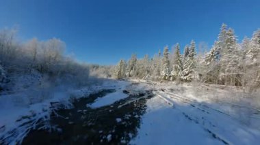 Fast flight along a mountain river surrounded by a snow-covered forest. Fairy winter mountain landscape on a frosty sunny day. Tatra Mountains, Zakopane, Poland. Filmed on FPV Drone