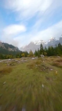 Dikey video. İsviçre Alpleri 'ndeki Oeschinensee Gölü üzerinde bulutlu bir sonbahar gününde FPV manevra kabiliyeti olan bir uçuş. Kandersteg, İsviçre.