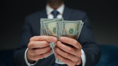 Resmi olarak giyinmiş bir adam Amerikan dolarlarını sayıyor, yakın plan. Yatırım, başarı, finansal beklentiler veya kariyer ilerlemesi kavramı.