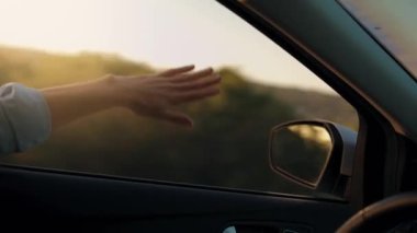 Araba penceresinden yola bak ve aracı kullanan ve müziği yenmek için el kol hareketi yapan adama bak. Güneşli gökyüzü, rahatlatıcı, yolculuğun tadını çıkaran ve havayı ve özgürlüğü hisseden. Maceraya doğru, tatile..