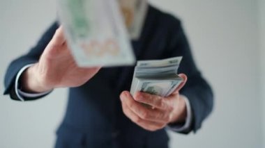 Formally dressed man makes money rain from US dollar bills. Slow motion. Concept of investment, success, financial prospects or career advancement