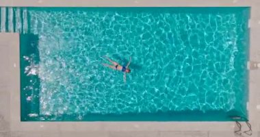 Top down view of a woman in a blue swimsuit lying on her back in the pool. Relaxing concept, summer lifestyle