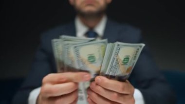 Resmi olarak giyinmiş bir adam Amerikan dolarlarını sayıyor, yakın plan. Yatırım, başarı, finansal beklentiler veya kariyer ilerlemesi kavramı.