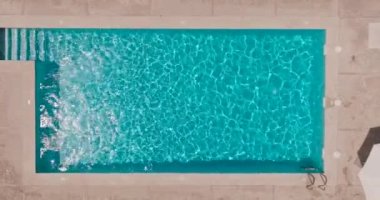 Yüzme havuzundaki saf mavi suyun yüzeyinde ışık yansımaları var. Hava görüntüleri