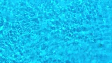Yüzme havuzundaki saf mavi suyun yüzeyinde ışık yansımaları var. Hava görüntüleri
