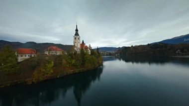 Bled Gölü 'nün üzerinde ve ortasında adanın etrafında hızla uçuyor. Slovenya, Bled Gölü 'nde Meryem' in Hacı Kilisesi. FPV insansız hava aracı ile vuruldu. Farklı hızda çekilmiş - normal ve