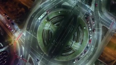 Sisli bir gecede kavşağın aşağısındaki araba trafiği manzarası. Kamera saat yönünde yükselir ve döner. Ulaşım teknolojisi, şehir hayatı.