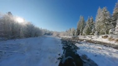 Fast flight along a mountain river surrounded by a snow-covered forest. Fairy winter mountain landscape on a frosty sunny day. Tatra Mountains, Zakopane, Poland. Filmed on FPV Drone
