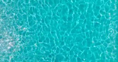 Yüzme havuzundaki saf mavi suyun yüzeyinde ışık yansımaları var. Hava görüntüleri