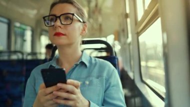 Toplu taşıma. Tramvaydaki gözlüklü kadın akıllı telefon konuşmaları yapıyor ve arkadaşlarıyla mesajlaşıyor. Şehir, şehir, ulaşım.