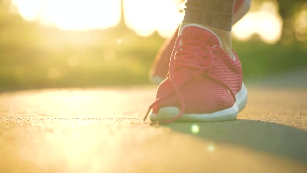 ジョギングや夕日を歩いている間に靴ひもを結ぶ女性は 閉じます スローモーション — ストック動画