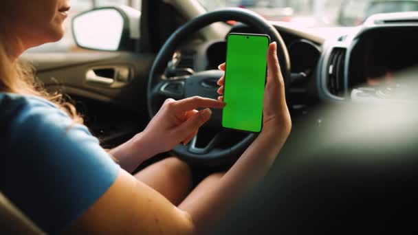 車内にスマートフォンを搭載した女性ドライバー 緑の画面でChromakeyスマートフォン 自動航法だ インターネット中毒 自動車保険の適用 — ストック動画