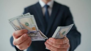 Resmi olarak giyinmiş bir adam Amerikan dolarlarını sayıyor, yakın plan. Yatırım, başarı, finansal beklentiler veya kariyer ilerlemesi kavramı.