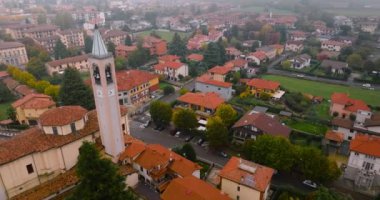 Milan ve Bergamo arasındaki kırsal alanın havadan görüntüsü. Küçük bir kasabada eski ve yeni binalar, kırmızı çatılar, ağaçlar ve sisli bir günde Adda nehri. Lombardy, İtalya.