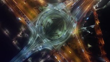 Sisli bir gecede kavşağın aşağısındaki araba trafiği manzarası. Kamera saat yönünün tersine iner ve döner. Ulaşım teknolojisi, şehir hayatı.