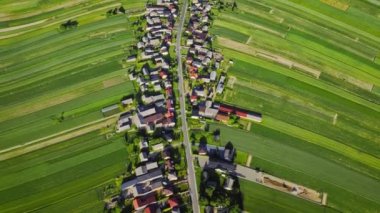 Aerial view of decorative ornaments of diverse green fields and houses arranged in a line along the road. Picturesque landscape, agriculture. Suloszowa, Poland