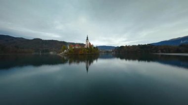 Bled Gölü 'nün üzerinde ve ortasında adanın etrafında hızla uçuyor. Slovenya, Bled Gölü 'nde Meryem' in Hacı Kilisesi. FPV insansız hava aracı ile çekildi. 