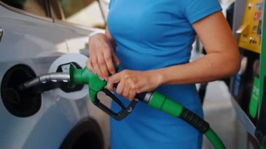 Kadın benzin deposuna yakıt doldurmak için yakıt tabancası yerleştiriyor. Artan benzin fiyatları ve akaryakıt krizi kavramı