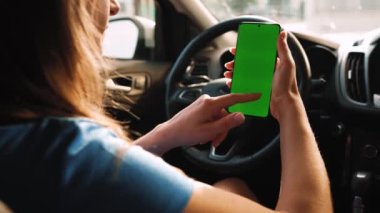 Kadın sürücü arabanın içinde akıllı telefon kullanıyormuş. Yeşil ekranlı Chromakey akıllı telefon. Otomatik navigasyon. İnternet bağımlılığı. Otomobil sigortası uygulaması.