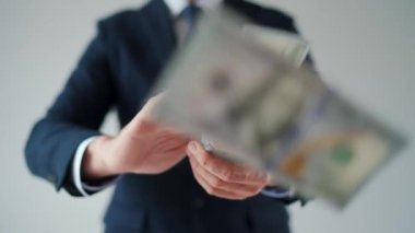 Formally dressed man makes money rain from US dollar bills. Slow motion. Concept of investment, success, financial prospects or career advancement