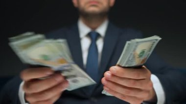 Resmi olarak giyinmiş bir adam Amerikan dolarlarını sayıyor, yakın plan. Yatırım, başarı, finansal beklentiler veya kariyer ilerlemesi kavramı.