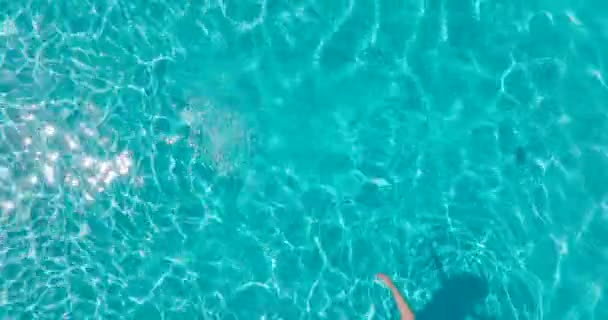 一个穿着黄色泳衣的女人躺在游泳池里的自上而下的照片 放松的概念 夏天的生活方式 相机在水面上升起 — 图库视频影像