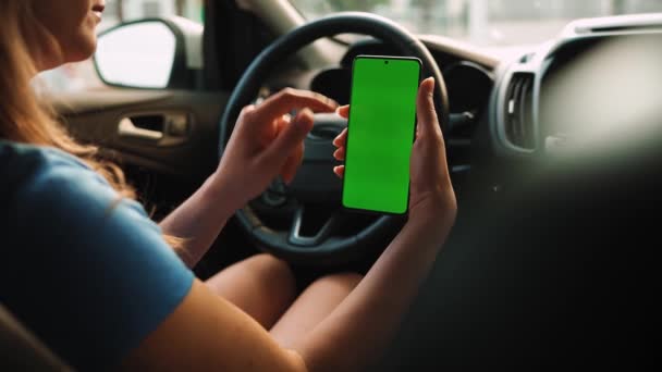 女司机在车里用智能手机 带有绿色屏幕的Chromakey智能手机 自动导航 上网成瘾 汽车保险申请 — 图库视频影像