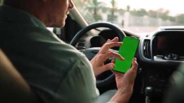 Erkek sürücü arabanın içinde akıllı telefon kullanıyor. Yeşil ekranlı Chromakey akıllı telefon. Otomatik navigasyon. İnternet bağımlılığı. Otomobil sigortası uygulaması.