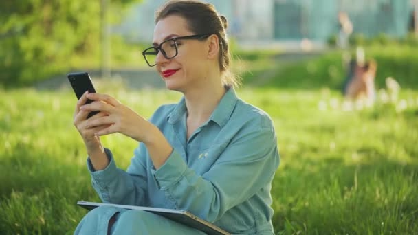 妇女在日落时完成室外工作后 坐在公园里使用智能手机 在室外工作的自由职业者 — 图库视频影像