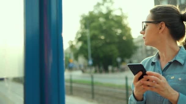 Женщина Стоит Остановке Общественного Транспорта Используя Смартфон Ждет Трамвай Город — стоковое видео