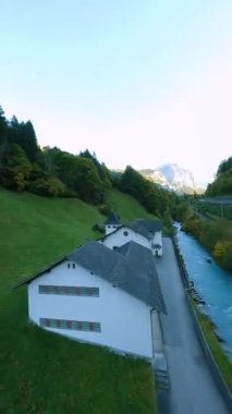 Dikey video. İsviçre 'de Lauterbrunnen Vadisi' nde kilise ve evler, Jungfrau bölgesinde İsviçre Alplerinde gün batımı, ünlü İsviçreli turist