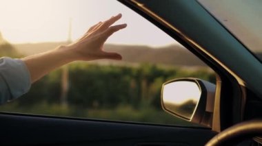 Araba penceresinden yola bak ve aracı kullanan ve müziği yenmek için el kol hareketi yapan adama bak. Güneşli gökyüzü, rahatlatıcı, yolculuğun tadını çıkaran ve havayı ve özgürlüğü hisseden. Maceraya doğru, tatile..