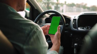 Erkek sürücü arabanın içinde akıllı telefon kullanıyor. Yeşil ekranlı Chromakey akıllı telefon. Otomatik navigasyon. İnternet bağımlılığı. Otomobil sigortası uygulaması.