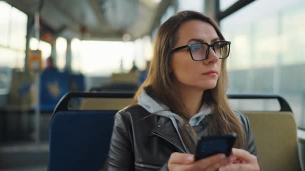 公共交通 坐在电车里戴眼镜的女人用智能手机和朋友聊天和发短信 — 图库视频影像