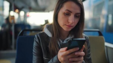 Public transport. Woman in glasses using smartphone chatting and texting with friends. City, urban, transportation.