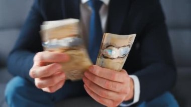 Formally dressed man counting Canadian Dollar bills, close-up. Concept of investment, success, financial prospects or career advancement.