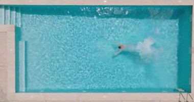 Top down view as a man dives into the pool and swims. Slow motion