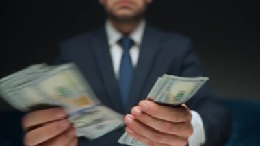 Resmi olarak giyinmiş bir adam Amerikan dolarlarını sayıyor, yakın plan. Yatırım, başarı, finansal beklentiler veya kariyer ilerlemesi kavramı.
