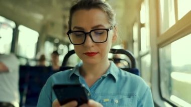 Toplu taşıma. Tramvaydaki gözlüklü kadın akıllı telefon konuşmaları yapıyor ve arkadaşlarıyla mesajlaşıyor. Şehir, şehir, ulaşım. Yavaş çekim